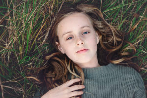 Portrait of girl laying in grass at Portchester Castle by Moira Lizzie Photography