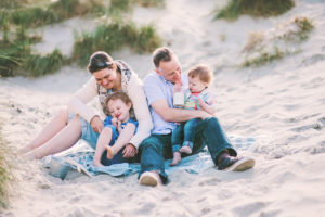 Family on blanket in sand dunes at East Head by Moira Lizzie Photography