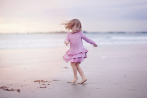 Gril spinning on sandy beach at sunset by Moira Lizzie Photography