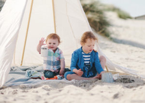 Siblings playing in sand on beach by Moira Lizzie Photography