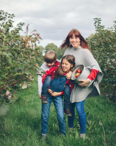 Relaxed portrait of family in apple orchard by Moira Lizzie Photography