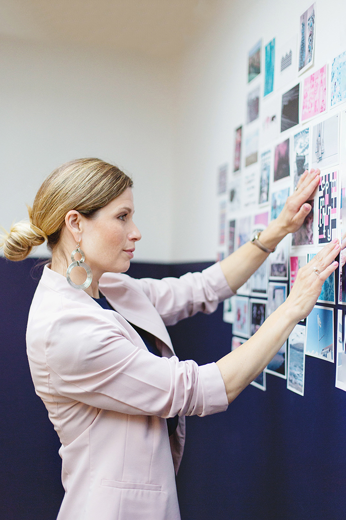 Personal branding image of business woman wearing pink jacket creating mood board on a  wall